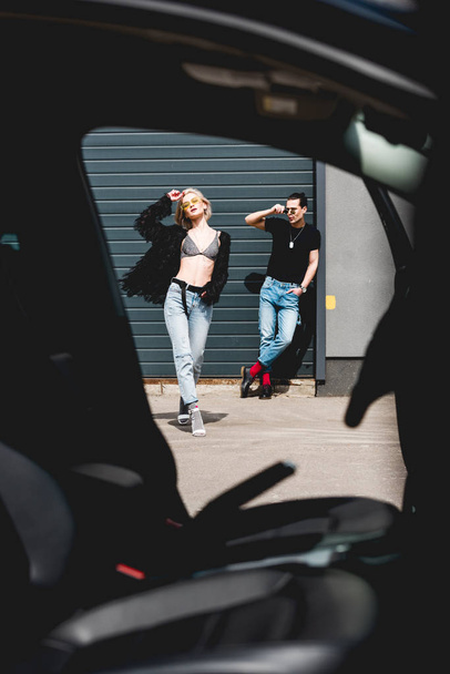 tyylikäs komea mies ja kaunis tyttö poseeraa ja elehtii lähellä autotalli
 - Valokuva, kuva