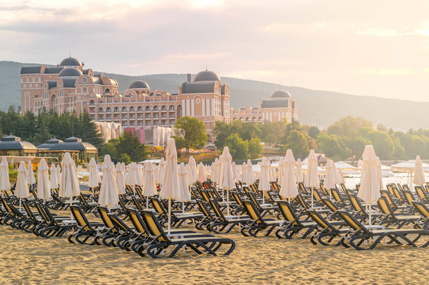Bulgaristan'ın Karadeniz kıyısında Sunny Beach gün doğumunda güzel bir plajda sandalye ve şemsiye. - Fotoğraf, Görsel