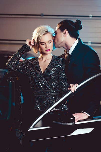stylish man kissing beautiful seductive woman near car - Fotografie, Obrázek