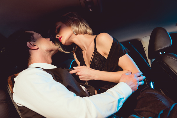 красивий стильний чоловік обіймає модну сексуальну молоду жінку в машині
 - Фото, зображення