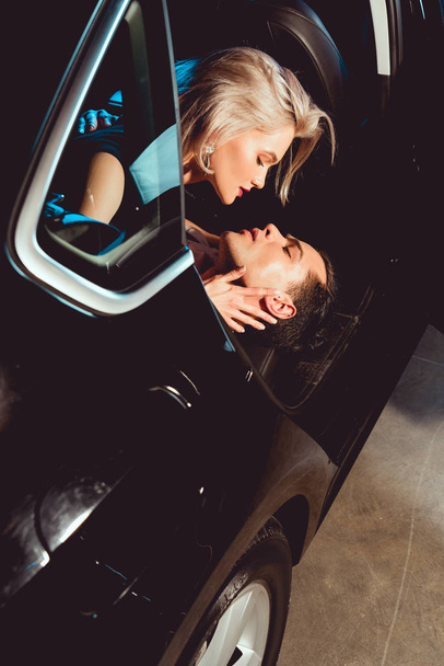 schöner Mann und attraktive junge Frau umarmen sich im Auto - Foto, Bild
