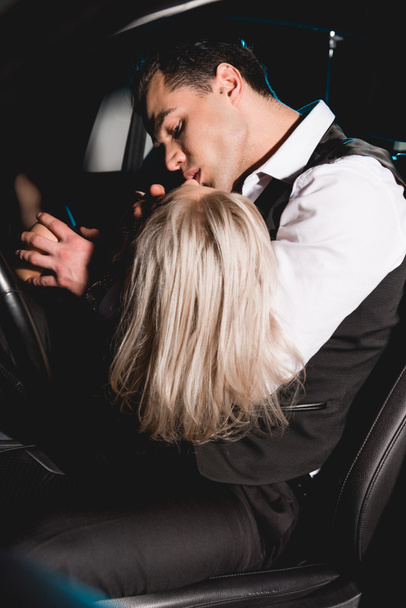 handsome man in formal wear kissing young woman in car - Photo, Image
