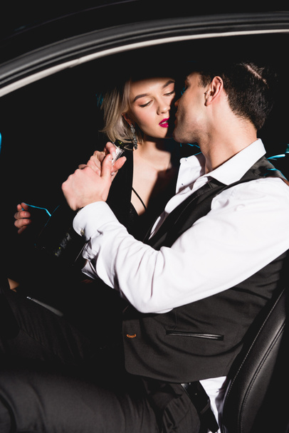 beautiful sensual couple in formal wear kissing in car - Photo, Image