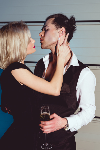 beautiful fashionable young woman embracing handsome man with champagne glass - Фото, изображение