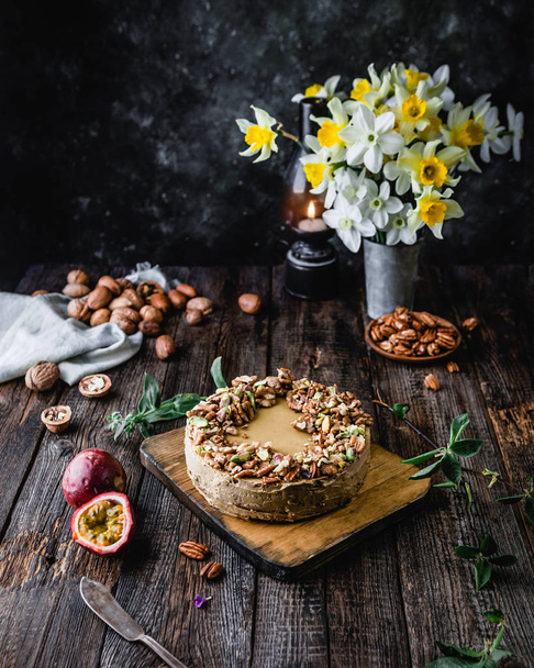 Cheesecake with nuts and maracuya with bouquet of yellow jonquils on background  - Photo, image