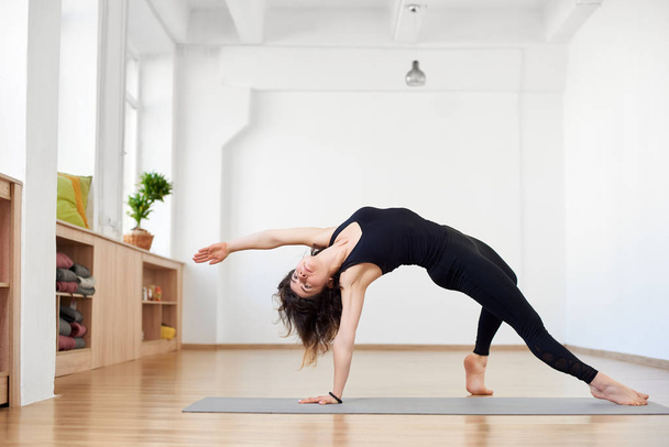 Fit sporty flexible girl doing backbend stretching exercise, Camatkarasana Wild Thing or Flip-the-Dog pose - Photo, Image
