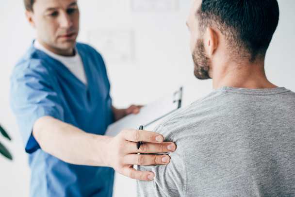 quiropráctico con diagnóstico examinando hombro de hombre en el hospital
 - Foto, Imagen