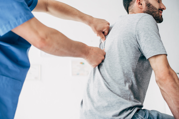 Physiotherapist massaging back of bearded man in hospital - Fotoğraf, Görsel
