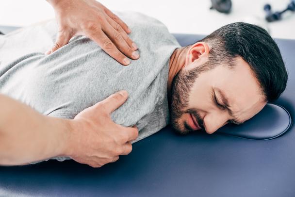 Хиропрактик массирует спину человека на массажном столе в больнице
 - Фото, изображение