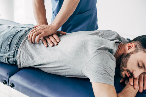 chiropractor massaging back of man on Massage Table in hospital - 写真・画像
