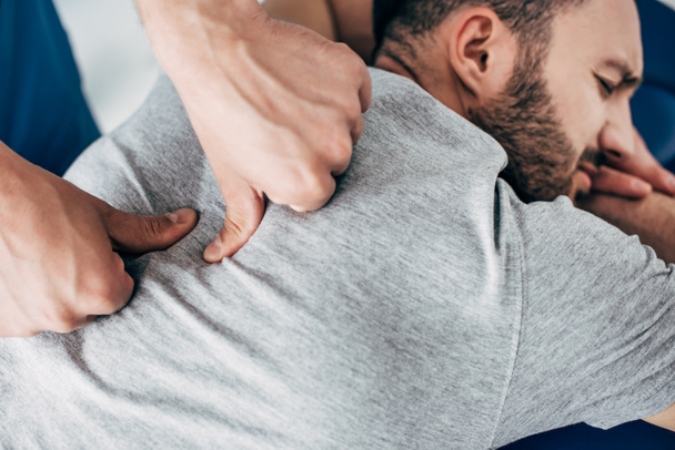 chiropractor massaging back of bearded man in hospital - Photo, Image
