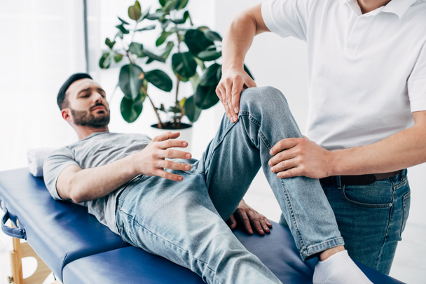 Physiotherapist massaging leg of patient lying on Massage Table in hospital - Фото, изображение
