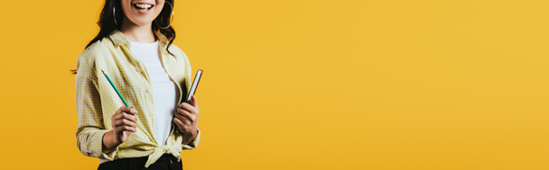 vista recortada de niña con cuaderno y pluma, aislado en amarillo
  - Foto, Imagen