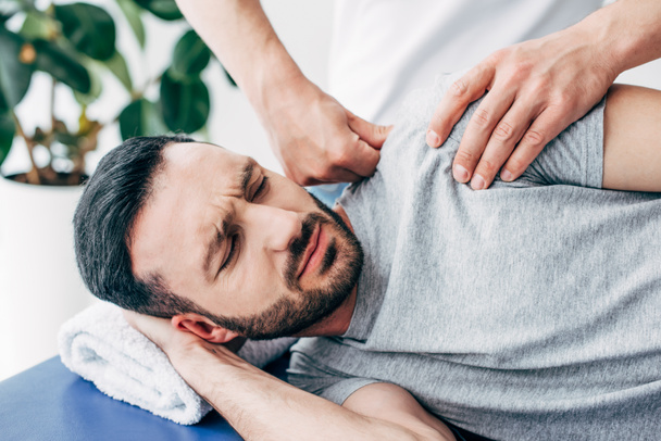 selective focus of chiropractor massaging shoulder of man in hospital - Fotó, kép
