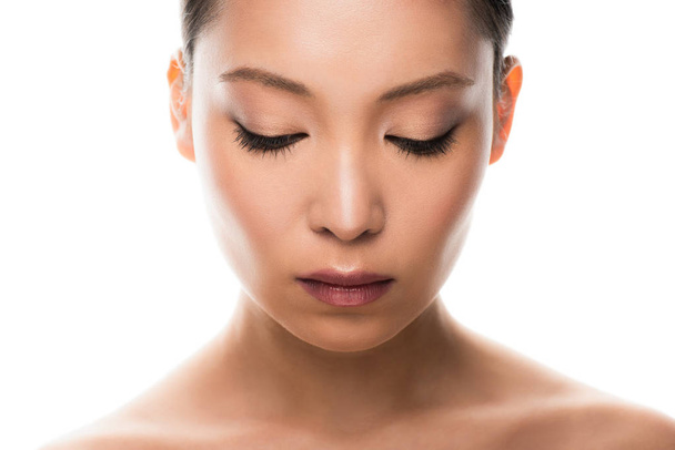 krásná mladá asijská žena s dokonalou kůží, která se dívá dolů, izolovaná na bílém - Fotografie, Obrázek