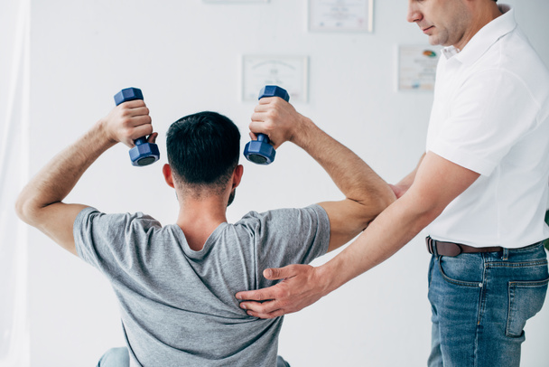 chiropraktik masírovat na rameni muže s činkami v nemocnici - Fotografie, Obrázek