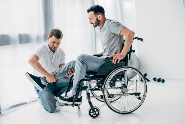 Physiotherapist massaging leg of handicapped man in wheelchair  - Foto, imagen