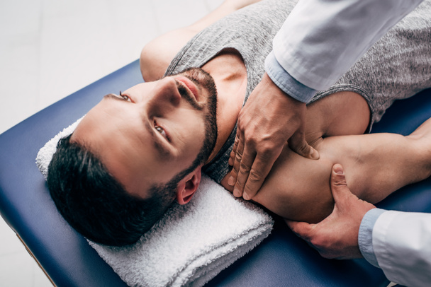 Хиропрактик массирует плечо мужчины на массажном столе в больнице
 - Фото, изображение