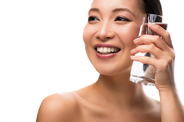mooie lachende vrouw die glas water vasthoudt, geïsoleerd op wit - Foto, afbeelding