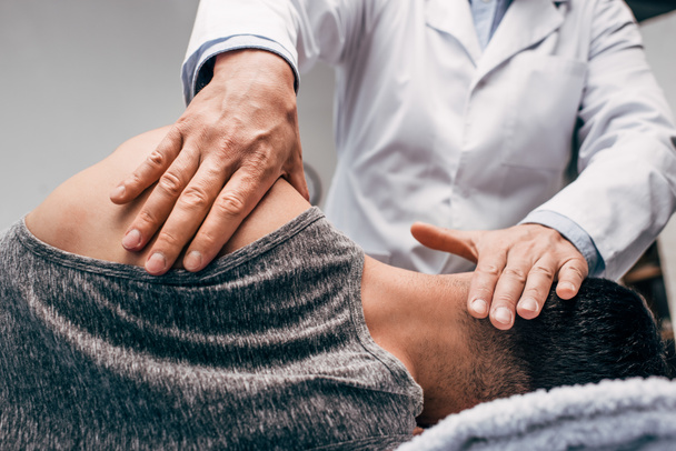 chiropractor in white coat massaging neck of man  - Photo, Image