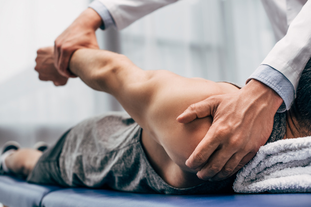selective focus of chiropractor stretching arm of patient in hospital - Photo, Image