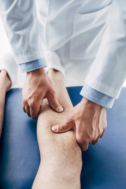 crpped view of Physiotherapist massaging leg of man in hospital - Fotó, kép