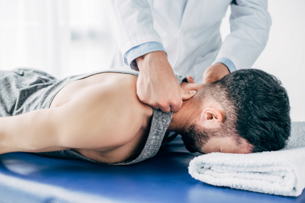 chiropraktik masírování krku člověka ležícího na masážní stůl s ručníkem - Fotografie, Obrázek