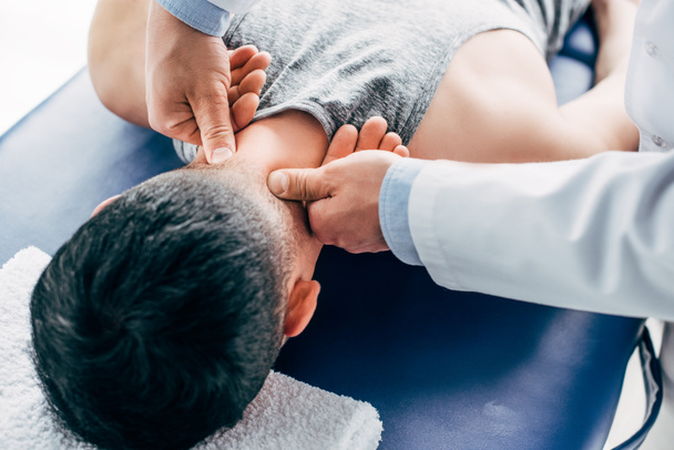 chiropracteur massant le cou de l'homme couché sur la table de massage avec serviette
 - Photo, image
