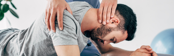 panoramic shot of chiropractor massaging neck of lying man  - Zdjęcie, obraz