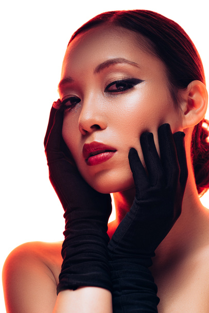 brunette asian girl in black gloves with makeup in red light, isolated on white - Foto, Imagem