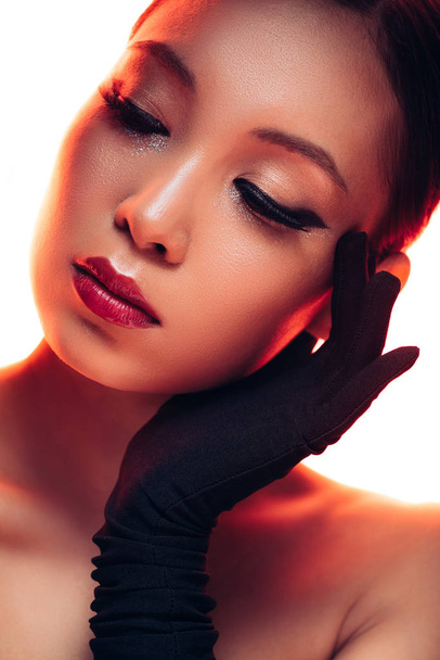 tender asian girl in black gloves with makeup in red light, isolated on white - Foto, imagen