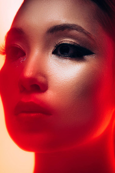 blízko krásné asijské dívky s make-upem v červeném světle  - Fotografie, Obrázek