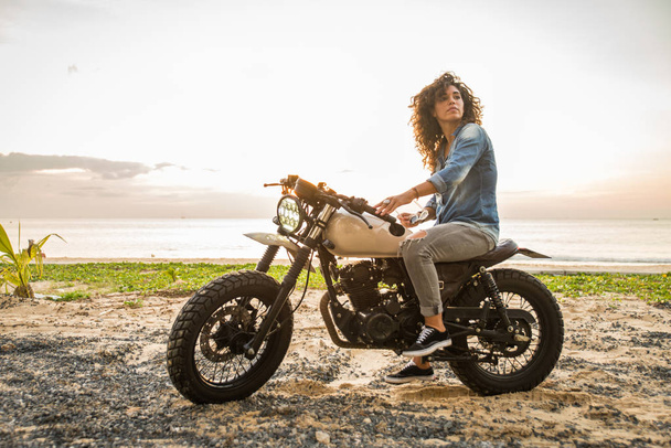 Female biker driving a cafe' racer motorbike - Valokuva, kuva