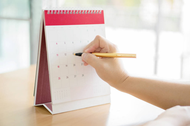 Woman hand carrying calendar and pointing on it by pen  - Foto, Imagen
