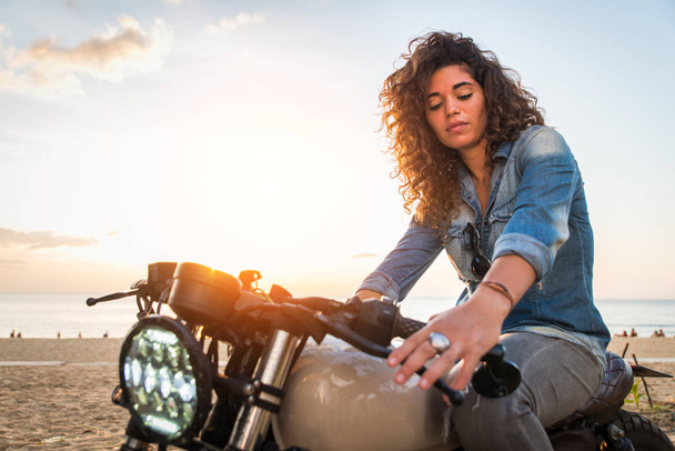 Female biker driving a cafe' racer motorbike - Фото, изображение