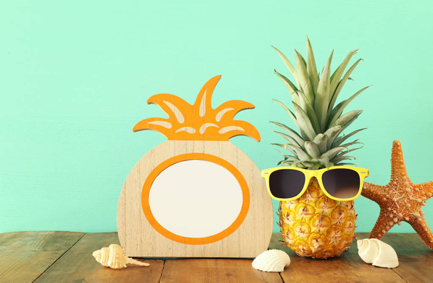 Empty photo frame and funny pineapple with sunglasses. For photography and scrapbook montage - Fotó, kép