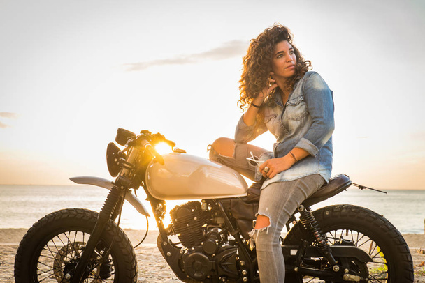 Female biker driving a cafe' racer motorbike - Фото, изображение