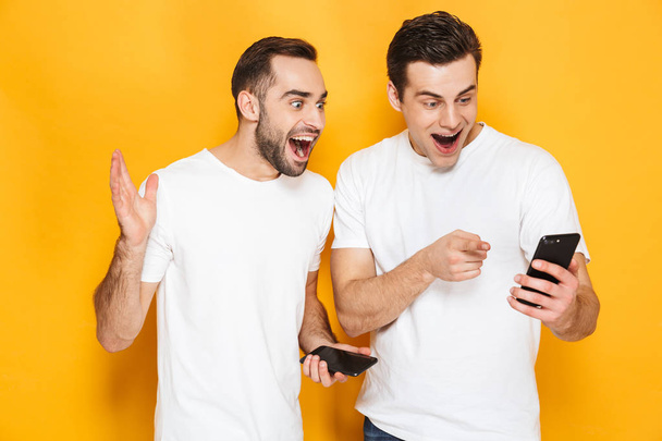 Dos alegres amigos excitados hombres que usan camisetas en blanco
 - Foto, imagen