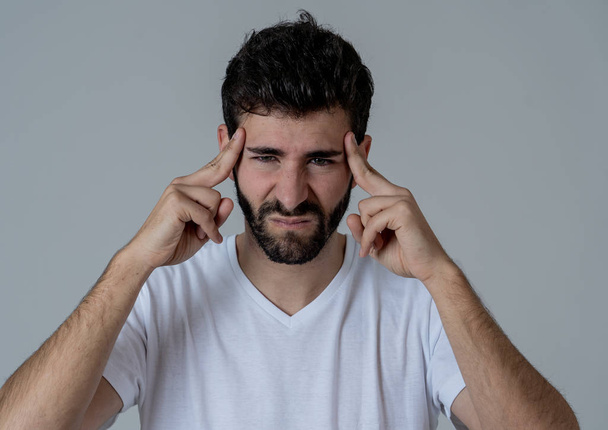 Close up portrait of a young man looking worried and thoughtful suffering from migraines in great pain. Isolated on neutral background. In facial expressions and emotions and heath care concept. - 写真・画像