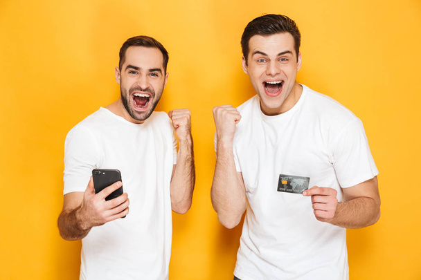 Two cheerful excited men friends wearing blank t-shirts - Фото, изображение