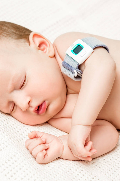 Baby girl in the crib measures body temperature. Mom measures the babys body temperature with a thermometer. - Foto, afbeelding