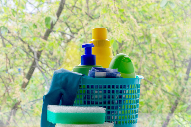 Reiniging. Mand met sponzen en flessen chemicaliën. Rubberen handschoenen en papieren handdoek. Huishoudelijke chemicaliën - Foto, afbeelding