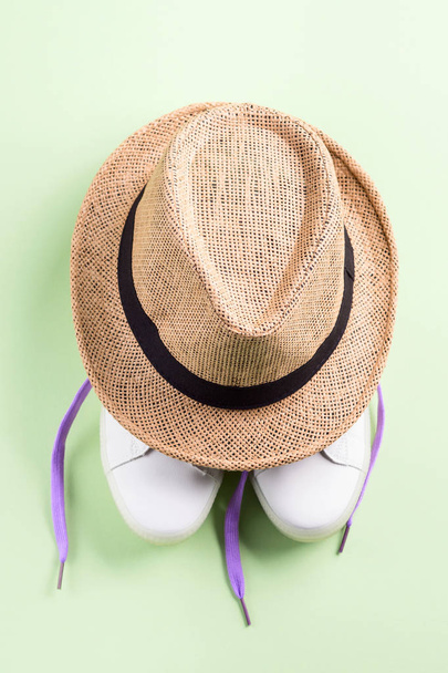 Sneakers bianche con lacci viola e cappello di paglia
 - Foto, immagini