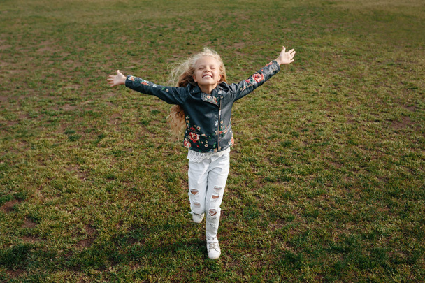 beautiful little child girl runs on a green lawn - Фото, зображення