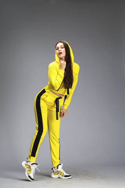 Portrait of a young beautiful brunette woman in yellow tracksuit - Фото, зображення