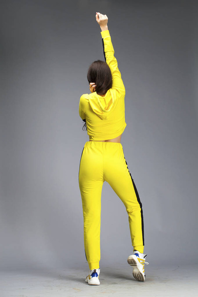 Portrait of a young beautiful brunette woman in yellow tracksuit - Фото, изображение