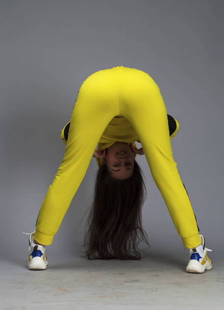 Portrait of a young beautiful brunette woman in yellow tracksuit - Foto, Bild