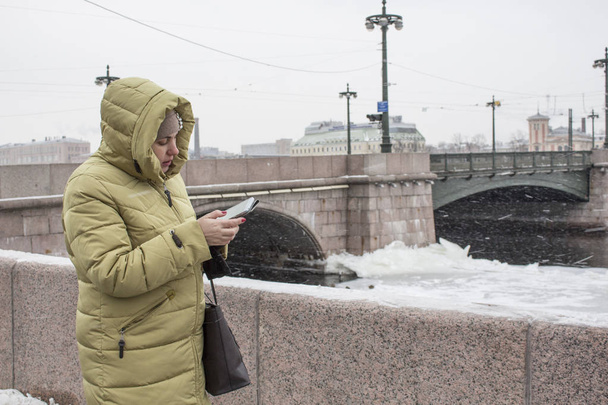  kaliningrad 2018.the girl with the phone stands at the bridge in winter - Foto, Imagen