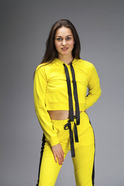 Portrait of a young beautiful brunette woman in yellow tracksuit - Foto, immagini