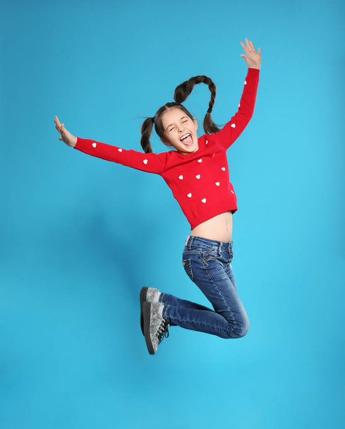 Portrait of little girl jumping on color background - Photo, Image